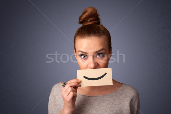 Happy pretty woman holding card with funny smiley Stock photo © ra2studio