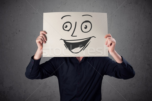 Businessman holding a cardboard with smiley face on it in front  Stock photo © ra2studio