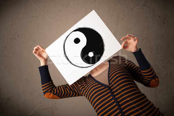 Woman holding a paper with a yin-yang on it in front of her head Stock photo © ra2studio