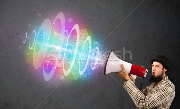 Man yells into a loudspeaker and colorful energy beam comes out Stock photo © ra2studio