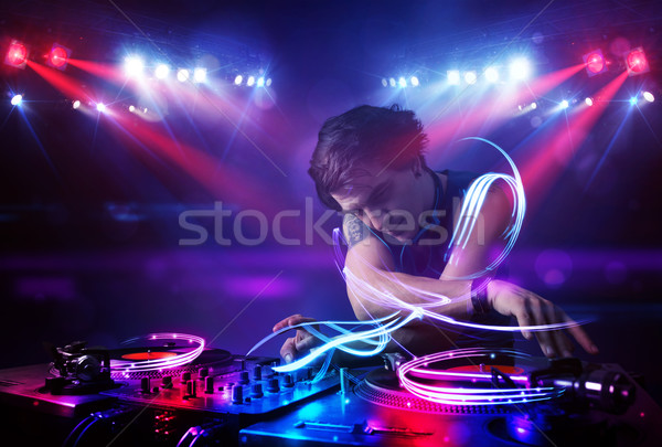 Disc jockey playing music with light beam effects on stage Stock photo © ra2studio
