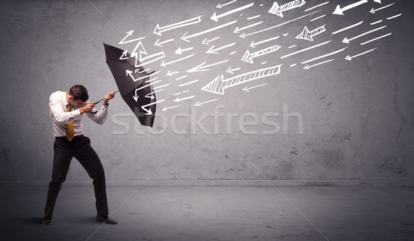 Business man standing with umbrella and drawn arrows hitting him Stock photo © ra2studio