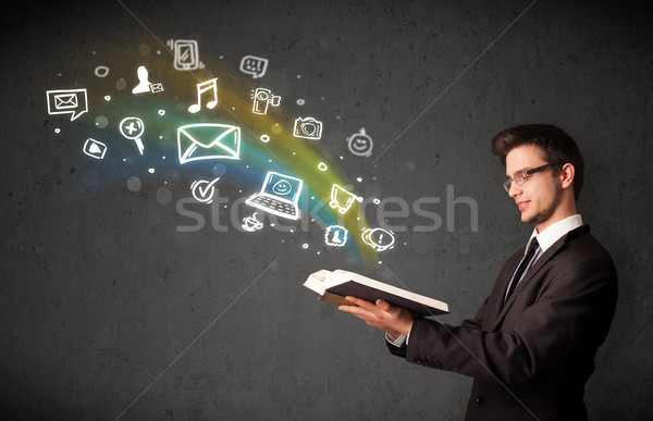 Stock photo: Businessman reading a book with multimedia icons coming out of the book