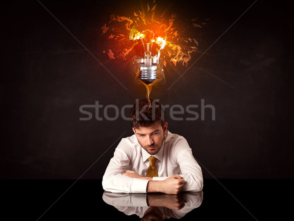 Businessman sitting under a blowing idea bulb Stock photo © ra2studio