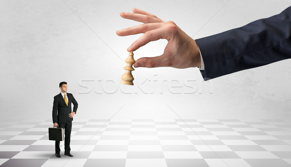 Stock photo: Businessman fighting against big chessman on a big hand