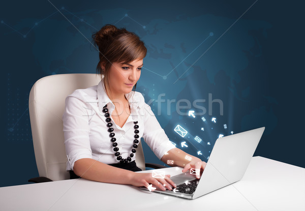Pretty young lady sitting at dest and typing on laptop with message icons comming out Stock photo © ra2studio