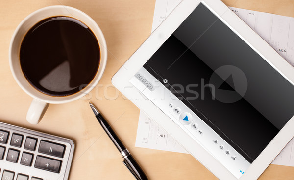 Workplace with tablet pc showing media player and a cup of coffee on a wooden work table closeup Stock photo © ra2studio