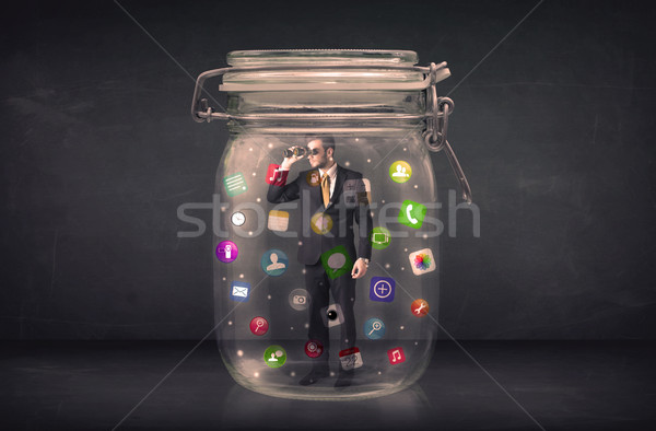 Businessman captured in a glass jar with colourful app icons con Stock photo © ra2studio