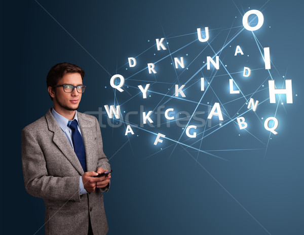 Handsome young man typing on smartphone with high tech 3d letters comming out Stock photo © ra2studio