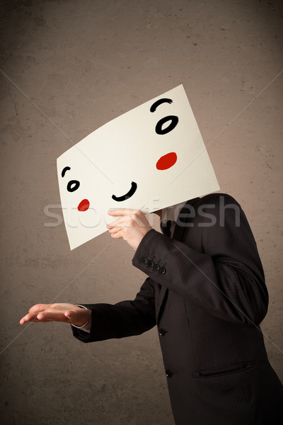 Businessman holding a cardboard with a smiley face on it Stock photo © ra2studio