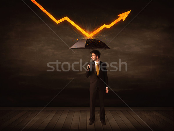 Stock photo: Businessman standing with umbrella keeping orange arrow 