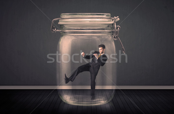 Stock photo: Businessman trapped into a glass jar concept