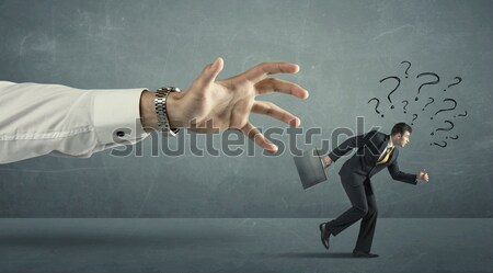 Businessman with question marks running away from a big hand  Stock photo © ra2studio