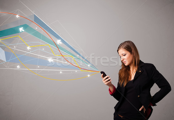 Stock photo: pretty young lady standing and holding a phone with colorful abstract lines and arrows