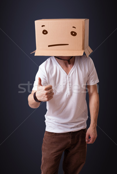 Young man gesturing with a cardboard box on his head with straig Stock photo © ra2studio