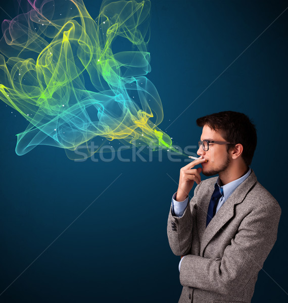 Handsome man smoking cigarette with colorful smoke Stock photo © ra2studio