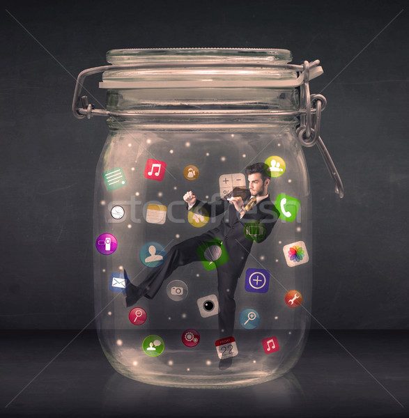 Businessman captured in a glass jar with colourful app icons con Stock photo © ra2studio