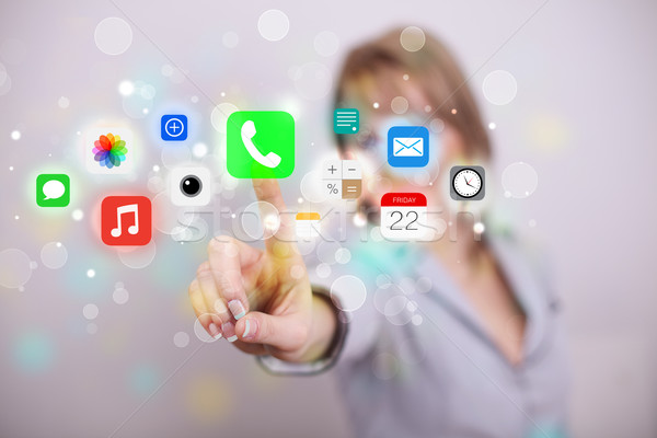 Young businesswoman pressing colorful mobile app icons with boke Stock photo © ra2studio