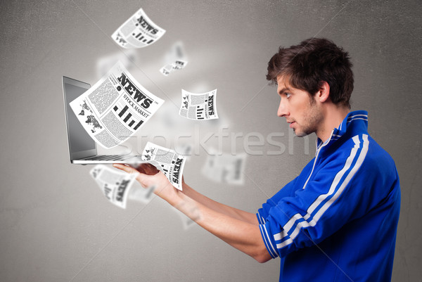 Young man holding a laptop and reading the explosive news Stock photo © ra2studio