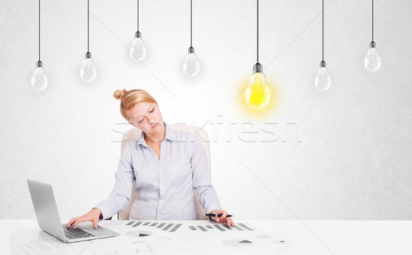 Business woman sitting at table with idea light bulbs Stock photo © ra2studio