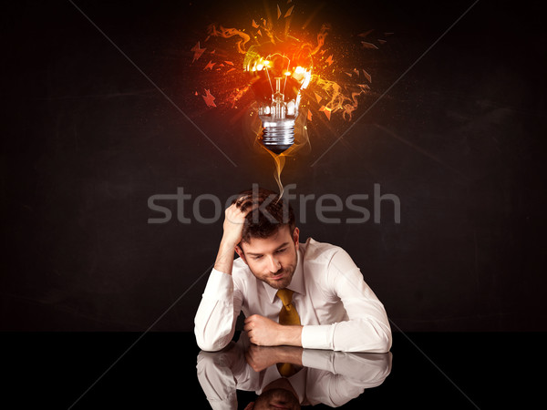 Businessman sitting under a blowing idea bulb Stock photo © ra2studio