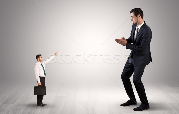 Small businessman pointing to a giant businessman Stock photo © ra2studio