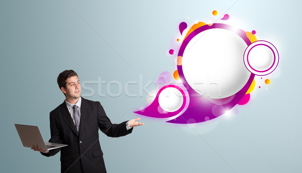Attractive young man holding a laptop and presenting abstract speech bubble copy space  Stock photo © ra2studio