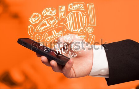 Stock photo: Hand holding phone with hand drawn speech bubbles