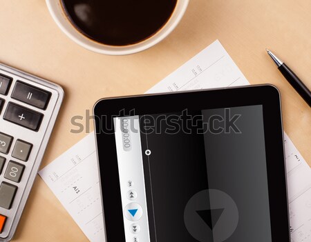 Workplace with tablet pc showing media player and a cup of coffee on a wooden work table closeup Stock photo © ra2studio