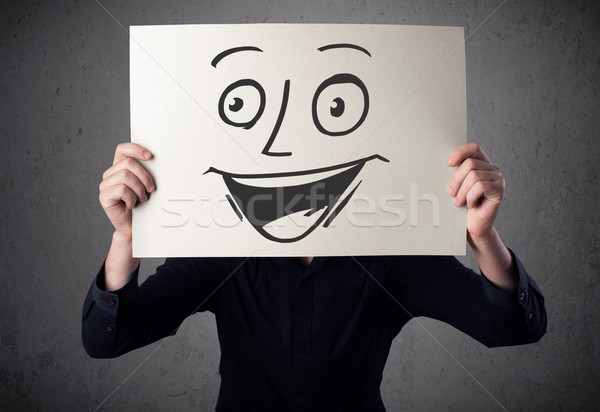 Businessman holding a cardboard with smiley face on it in front  Stock photo © ra2studio