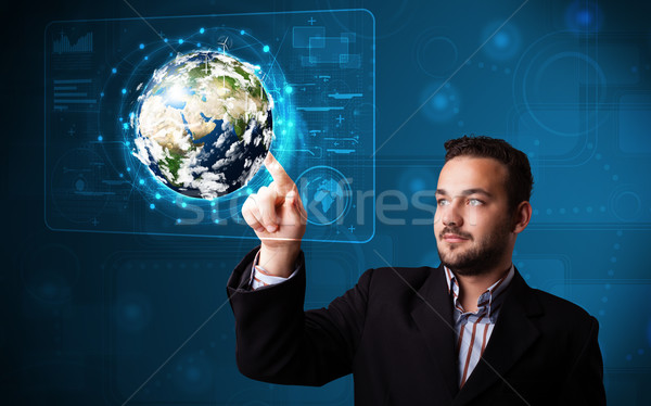 Young businessman touching high-tech 3d earth panel Stock photo © ra2studio