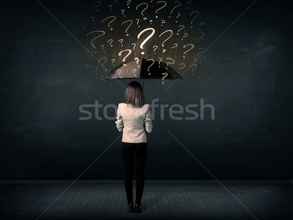 Stock photo: Businesswoman with umbrella and a lot of drawn question marks