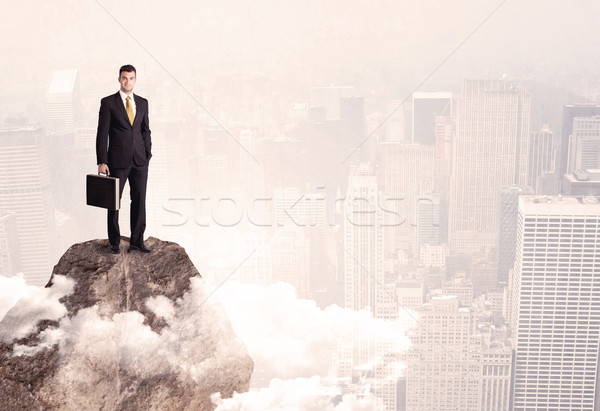 Happy businessman standing on stone top Stock photo © ra2studio