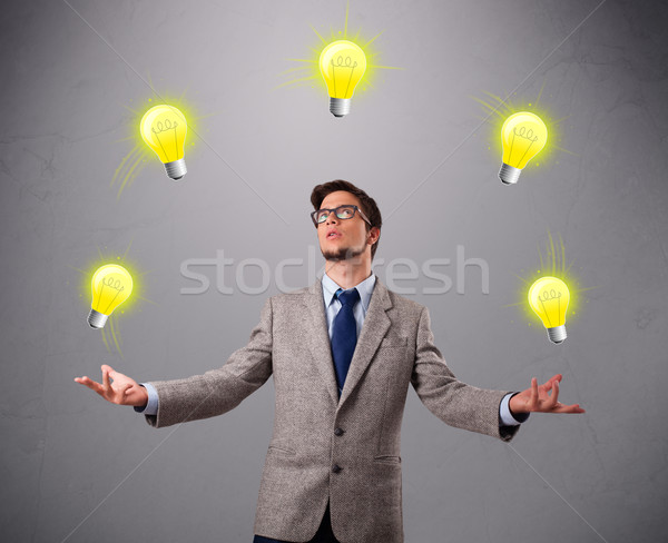 young man standing and juggling with light bulbs Stock photo © ra2studio