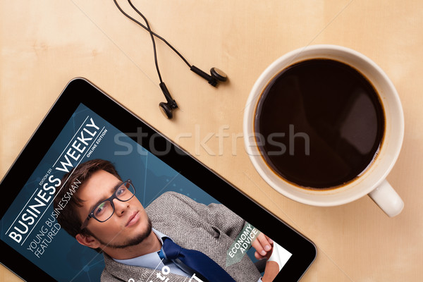 Workplace with tablet pc showing magazine cover and a cup of coffee on a wooden work table closeup Stock photo © ra2studio
