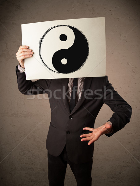 Businessman holding a paper with a yin-yang on it in front of hi Stock photo © ra2studio