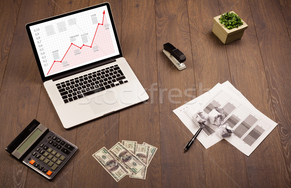 Computer desk with laptop and red arrow chart in screen Stock photo © ra2studio