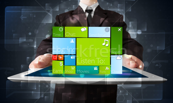 Stock photo: Young businessman holding a tablet with modern software operational system