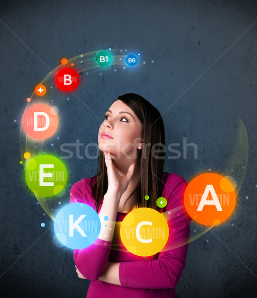 Young woman thinking with vitamins circulation around her head Stock photo © ra2studio