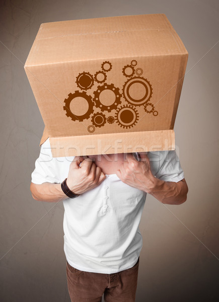 Young man gesturing with a cardboard box on his head with spur w Stock photo © ra2studio