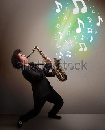 Young musician playing on saxophone while musical notes explodin Stock photo © ra2studio