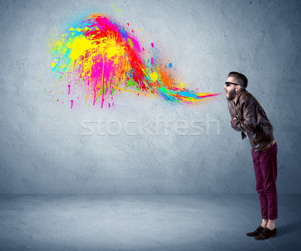 Stock photo: Hipster guy shouting colorful paint on wall