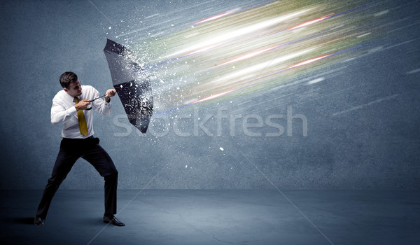 Stock photo: Business man defending light beams with umbrella concept