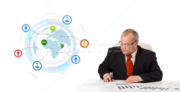 businessman sitting at desk with a globe and social icons Stock photo © ra2studio