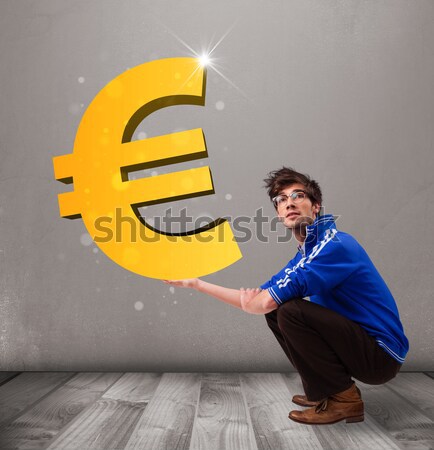 Good-looking boy holding a big 3d gold euro sign Stock photo © ra2studio
