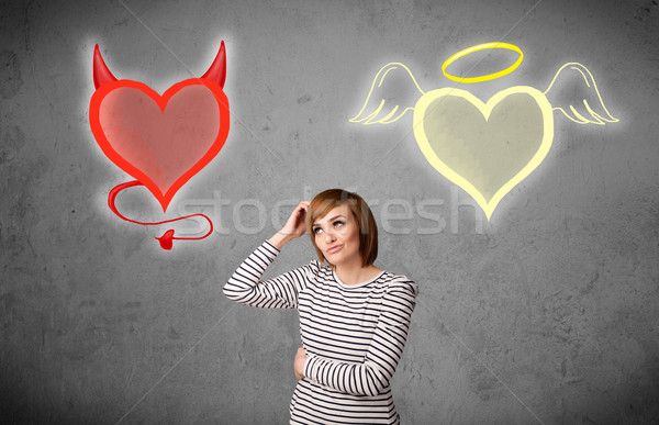 Woman standing between the angel and devil hearts Stock photo © ra2studio