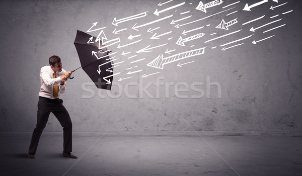 Business man standing with umbrella and drawn arrows hitting him Stock photo © ra2studio