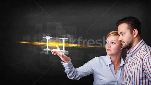 Young tech business couple touching button with orange light bea Stock photo © ra2studio
