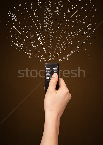 Hand with remote control and curly lines Stock photo © ra2studio