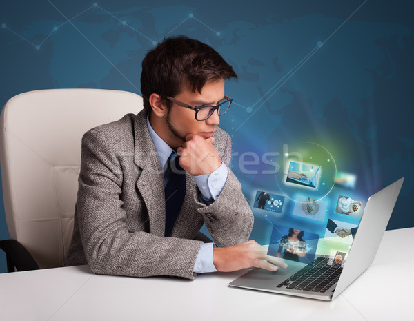 Attractive young man sitting at desk and watching his photo gallery on laptop Stock photo © ra2studio